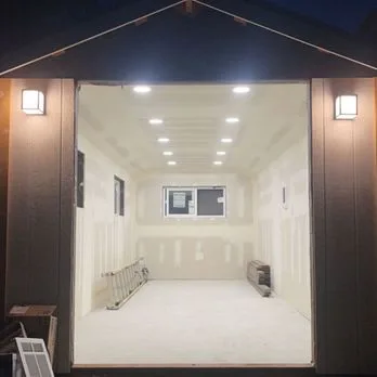 Detached shop at dusk: exterior sconces and interior recessed lighting